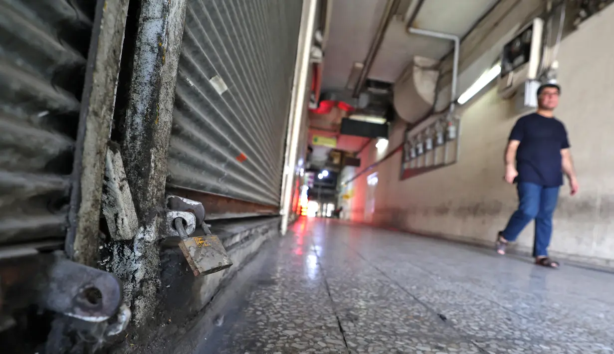 Seorang pria Iran berjalan melewati toko-toko yang tutup di pusat komersial di pusat kota Teheran, Selasa (20/7/2021). Iran memberlakukan lockdown di ibu kota Teheran dan provinsi terdekat setelah kasus infeksi Covid-19 mencapai rekor tertingginya selama wabah kelima. (ATTA KENARE/AFP)