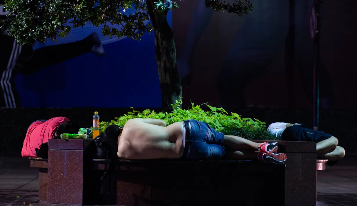 Sejumlah pria tidur di bangku di sepanjang Nanjing East Road, Shanghai (8/8). Nanjing East Road yang biasanya ramai oleh pembeli dan turis berubah menjadi pesta tidur terbuka pada malam hari. (AFP Photo/Johannes Eisele)