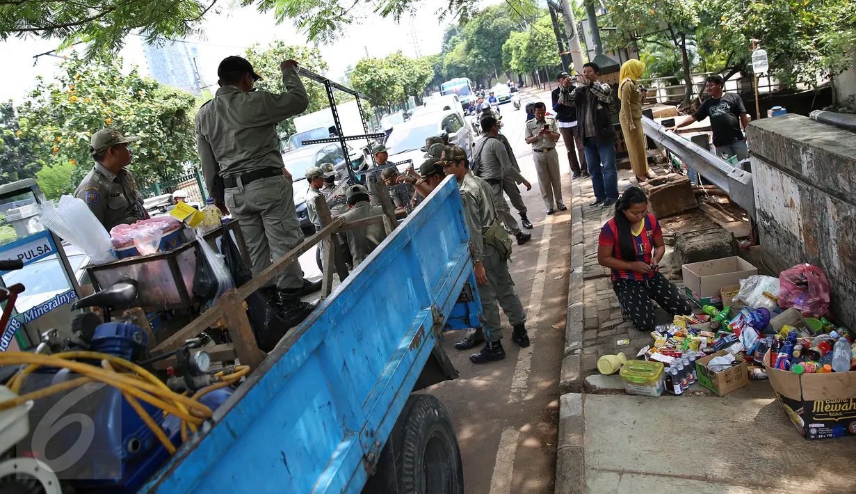 Seorang Pedagang merapikan barang daganggannya saat Petugas Satpol PP menertibkan lapak pedagang kaki lima (PKL) di pinggir jalan Kawasan Palmerah, Jakarta, Senin (17/10). Aktifitas ini dilakukan Satpol PP kelurahan Gelora. (Liputan6.com/Johan Tallo)