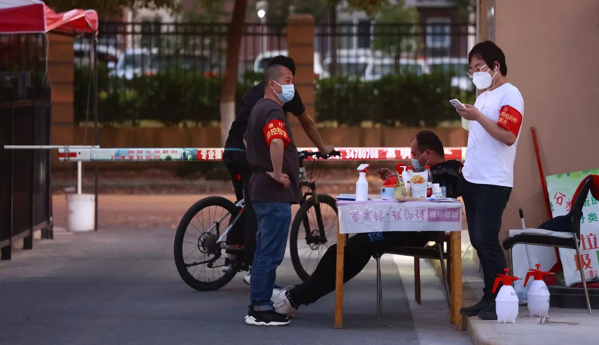 Relawan yang mengenakan ban lengan dan masker wajah berdiri di gerbang komunitas perumahan di Shanghai, China (11/4/2022). AS telah memerintahkan semua staf konsuler non-darurat untuk meninggalkan Shanghai, yang berada di bawah penguncian ketat untuk menahan COVID -19 lonjakan. (AP Photo)