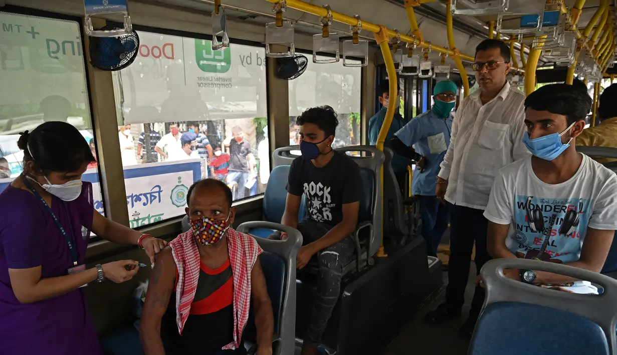 Seorang petugas kesehatan menyuntik pekerja dengan vaksin Covid-19 Covishield di dalam bus penumpang yang diubah menjadi pusat vaksinasi keliling di Kolkata, Kamis (3/6/2021). India telah menderita pandemi yang menghancurkan sejak April, dan baru-baru ini mulai mereda. (Dibyangshu SARKAR/AFP)