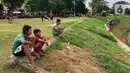 Anak-anak bermain di sekitar bantaran Kanal Banjir Timur (KBT), kawasan Cipinang Muara, Jakarta, Selasa (16/6/2020). Sebagian besar warga masih mengabaikan protokol kesehatan dengan tidak menjaga jarak serta tanpa menggunakan masker. (Liputan6.com/Immanuel Antonius)