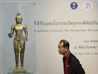 Seorang warga Thailand melihat patung Siwa berdiri dari abad ke-11 saat upacara pemulangan di Museum Nasional di Bangkok, Thailand, Selasa (21/5/2024). (AP Photo/Sakchai Lalit)