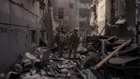 Prajurit Ukraina berjalan di antara puing-puing bangunan yang rusak setelah serangan Rusia di Kharkiv, Ukraina, 16 April 2022. Sejak invasi Rusia ke Ukraina, perang terus berkecamuk hingga bulan ini, Februari 2023. (AP Photo/Felipe Dana, File)