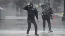 <p>Pejalan kaki diterpa angin dan hujan saat menyeberang jalan di Boston, Amerika Serikat, Senin (18/12/2023). Badai yang bergerak di Pantai Timur membawa hujan lebat dan angin kencang ke Timur Laut pada hari Senin, mengancam banjir dan memadamkan listrik ke ratusan ribu rumah. (AP Photo/Steven Senne)</p>