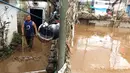 Warga mendorong lumpur sisa banjir yang menggenangi rumahnya di kawasan Rawajati, Jakarta Selatan, Selasa (6/2). Sebelumnya, banjir setinggi dua meter merendam kawasan tersebut. (Liputan6.com/Immanuel Antonius)