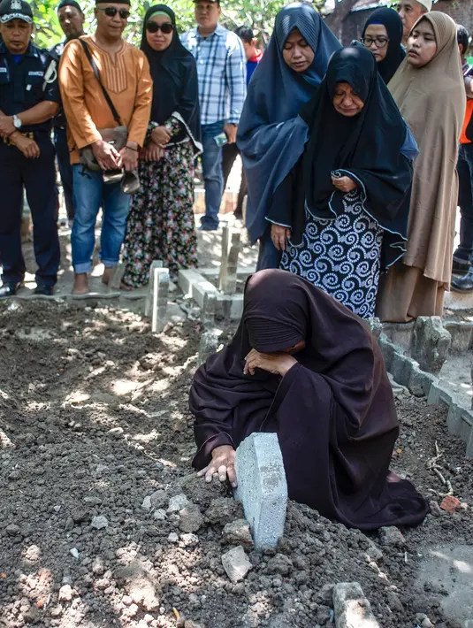 Bibi (kanan bawah) dari penyelam Syachrul Anto yang meninggal dunia kala melakukan evakuasi jatuhnya pesawat Lion Air PK-LQP, berdoa saat pemakaman di Surabaya, Jawa Timur, Sabtu (3/11). Syachrul Anto meninggal karena dekompresi. (JUNI KRISWANTO/AFP)