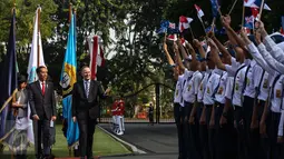 Presiden Joko Widodo berjalan bersama Perdana Menteri Selandia Baru John Key disambut pelajar yang mengibarkan bendera saat upacara penyambutan di Halaman Istana Merdeka, Jakarta, Senin (18/7). (Liputan6.com/Faizal Fanani)