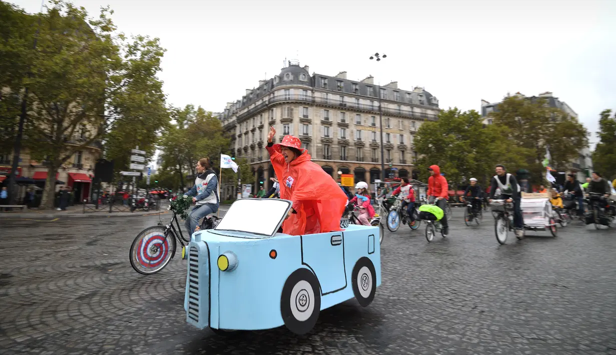 Seorang wanita mengemudikan sepeda yang dihias dengan kardus berbentuk mobil di Place de la Bastille, Paris, Prancis (1/10). Acara hari bebas kendaraan bermotor di Paris ini telah di gelar ketiga kalinya. (AFP Photo/Eric Feferberg)