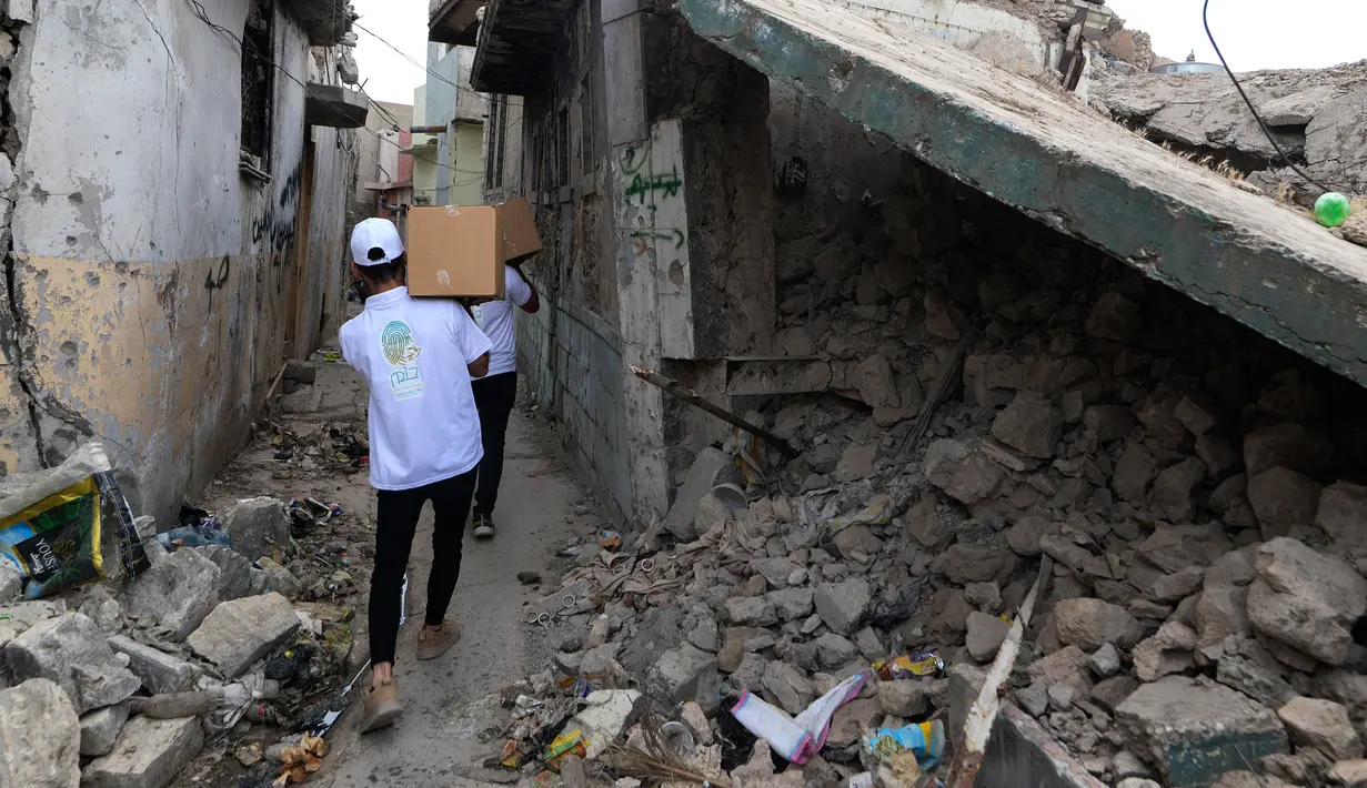 Para relawan Irak di asosiasi lokal saat mendistribusikan jatah makanan ke rumah tangga selama bulan Muslim Ramadhan di kota Mosul utara (7/5/2021). (AFP Photo/Zaid AL-Obeidi)