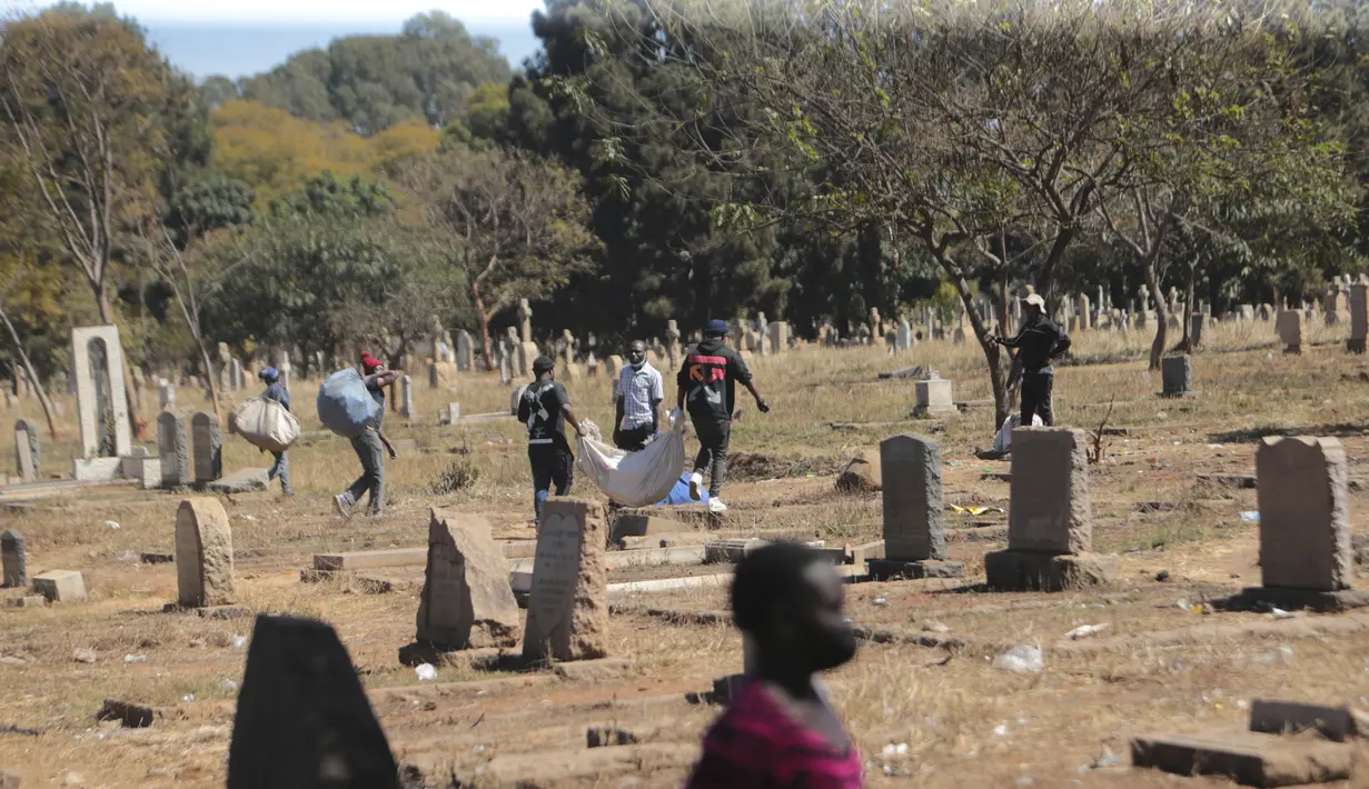 Pedagang Zimbabwe membawa dagangannya di kuburan setelah kabur dari kejaran polisi yang mengejar mereka setelah kedapatan berjualan dari tempat yang tidak ditentukan karena pembatasan COVID-19 di Harare, Kamis (29/7/2021). (AP Photo/Tsvangirayi Mukwazhi)