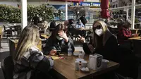 Para perempuan mengobrol sambil menunggu pesanan mereka di restoran yang dibuka kembalidi Ankara, Turki, Selasa (2/3/2021). Aktivitas bisnis seperti kafe dan restoran, diizinkan dibuka kembali dengan pembatasan kapasitas jumlah pengunjung serta jam operasional. (AP Photo/Burhan Ozbilici)
