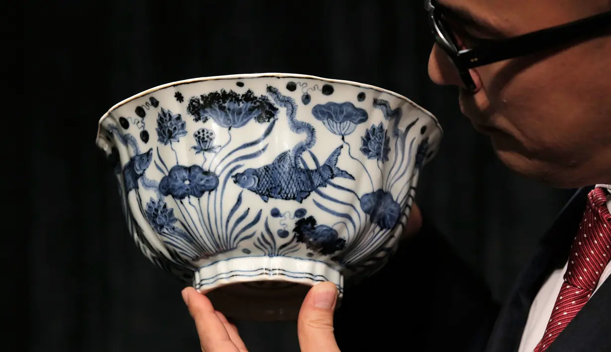  Pekerja memegang sebuah mangkuk Xuande Lobel "Fish Pond" saat ditampilkan di pelelangan Sotheby di Hong Kong (8/3). Mangkuk ini diperkirakan akan terjual dengan harga lebih dari USD 12,8 juta atau sekitar Rp 171 miliar. (AP Photo / Kin Cheung)