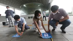 Para pekerja menempelkan tanda-tanda jarak sosial di lantai Museum Nasional Korea di Seoul, Korea Selatan, Rabu (22/7/2020). Museum ini dibuka kembali pada Rabu (22/7) setelah ditutup selama dua bulan akibat pandemi corona Covid-19. (AP Photo/Ahn Young-joon)