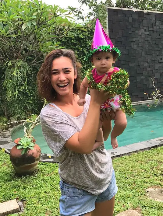 Aktris cantik yang satu ini memang hobi banget memamerkan bentuk tubuhnya yang seksi. Terlebih dengan warna kulitnya yang eksotis. Terlihat saat ia menggendong gadis mungilnya memakai short pants ini. (Instagram/got_alex)