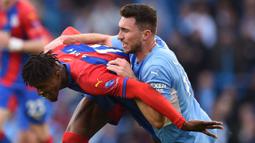 Alih-alih bangkit, Manchester City malah harus bermain dengan 10 pemain setelah Aymeric Laporte (kanan) diganjar kartu merah. Apesnya lagi, The Citizen harus kebobolan di babak kedua lewat gol  Wilfried Zaha (kiri). (AFP/Oli Scarff)