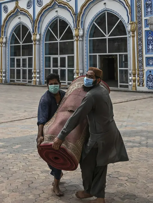 Umat Muslim melepas karpet sajadah dari aula utama masjid menyusul pembatasan baru pemerintah baru menjelang Ramadan di Rawalpindi, Pakistan, Senin (5/4/2021). Sesuai pedoman, karpet atau permadani tidak akan digunakan di masjid dan salat akan dilakukan di lantai tanpa karpet. (Aamir QURESHI/AFP)