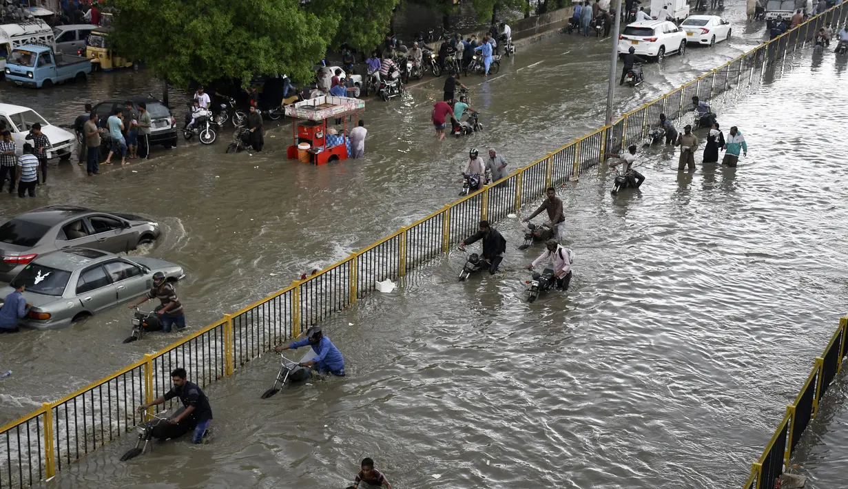 Para pengendara mendorong kendaraannya saat melewati jalan yang banjir di Karachi, Pakistan, Kamis (23/9/2021). Banjir merendam Karachi setelah diguyur hujan deras. (AP Photo/Fareed Khan)
