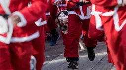 Seekor anjing bersama pemiliknya berpakaian Santa Claus saat mengikuti perlombaan lari tradisional Santa Claus Tahun Baru di Skopje, (24/12) (AFP Photo / Robert Atanasovki)