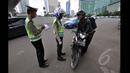 Petugas kepolisian menilang seorang pengendara motor yang menerobos Jalan MH Thamrin, Jakarta, Minggu (18/1/2015). (Liputan6.com/Miftahul Hayat)