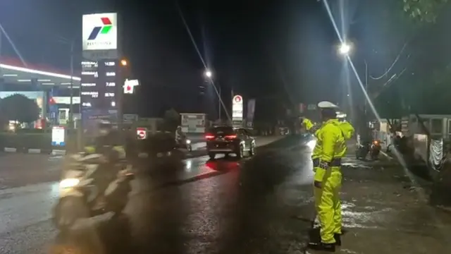 Di tengah guyuran hujan rincik yang membasahi langit Garut, sejak Sabtu petang, tak merintangi petugas jaga mengamankan jalur mudik nasional Limbangan-Malangbong, Garut, Jawa Barat. (Liputan6.com/Jayadi Supriadin)