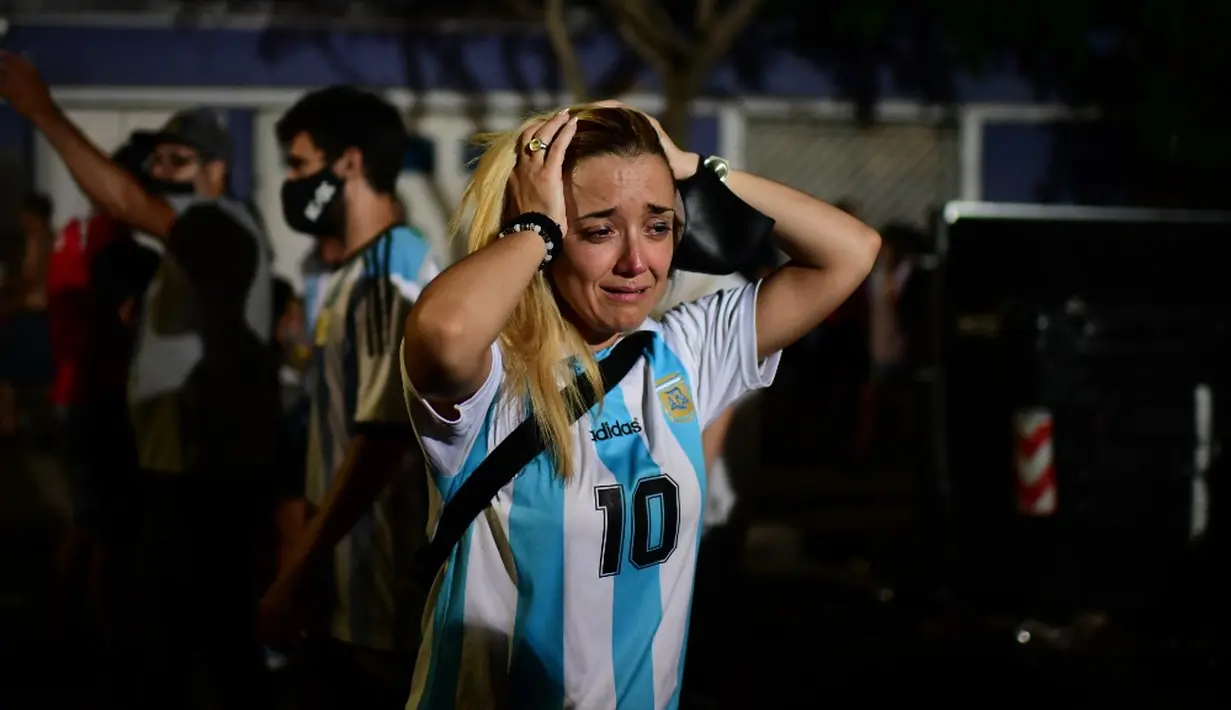 Fans legenda sepak bola Argentina Diego Maradona menangis saat berkumpul dengan penggemar lain untuk memberi penghormatan pada hari kematiannya di Argentinos Junior's Diego Armando Maradona Stadium di La Paternal, Buenos Aires, Argentina, 25 November 2020. (RONALDO SCHEMIDT/AFP)