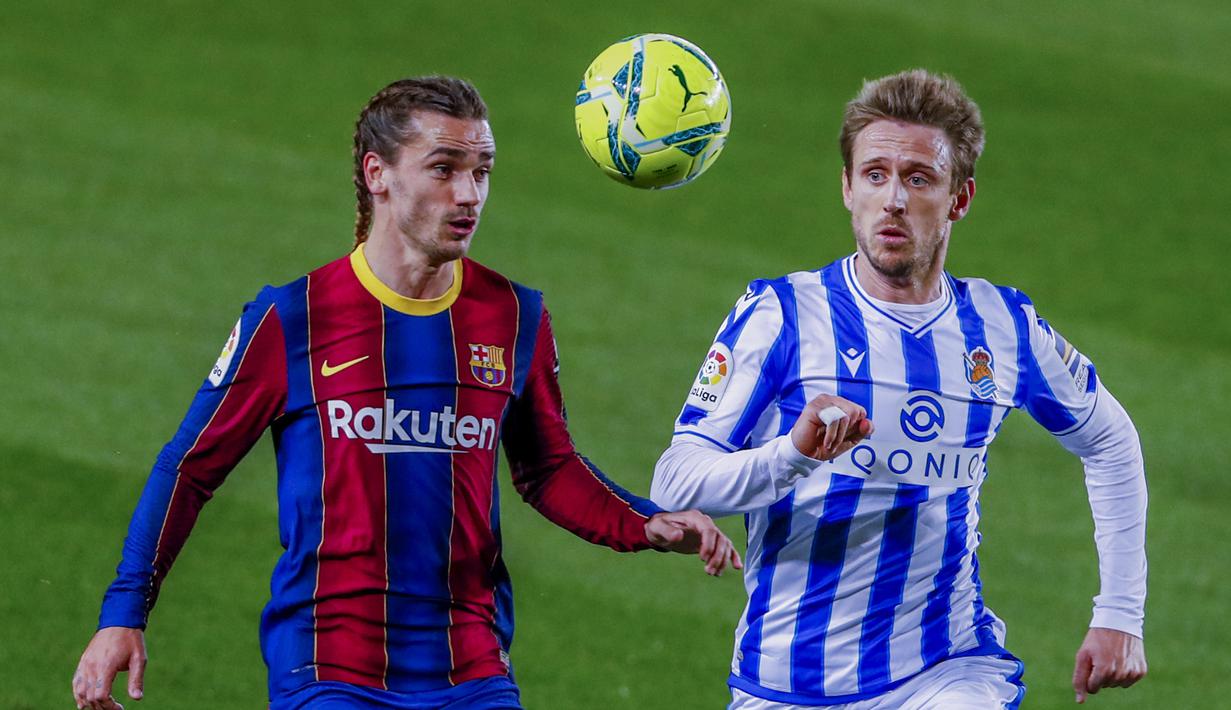 Penyerang Barcelona, Antoine Griezmann berebut bola dengan pemain Real Sociedad, Nacho Monreal pada pertandingan lanjutan La Liga Spanyol di stadion Camp Nou di Barcelona, Spanyol, Kamis (17/12/2020). Rambut kepang dua Griezmann juga dipamerkan dalam akun Instagram klub. (AP Photo/Joan Monfort)