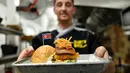 Koki Irlandia, Colin Kelly berpose dengan burger "Kim Jong Yum" di restoran Durty Bird, Hanoi, Vietnam, 21 Februari 2019. Menu baru ini terinspirasi pertemuan puncak antara Presiden AS Donald Trump dan pemimpin Korut, Kim Jong-un. (Manan VATSYAYANA/AFP)