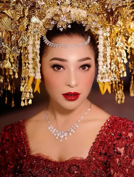 Nikita Willy ketika menjadi pengantin dibalut kebaya merah yang megah nan memesona. Makeup flawless dan sapuan lipstik merah dan sigar emas yang mewah menambah pesona Nikita Willy di momen ini. [Foto: Instagram/marlenehariman]