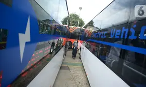 Petugas berjalan melintasi bus listrik Transjakarta saat peluncuran uji coba bus tersebut di Pool Transjakarta, Terminal Kampung Rambutan, Jakarta, Rabu (8/6/2022). Bus listrik itu akan melalui rute di jalur non Bus Rapid Transit (BRT) yang belum pernah dilalui bus listrik. (merdeka.com/Imam Buhori)
