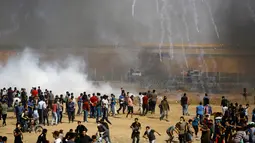 Sekelompok demonstran Palestina berlarian saat ditembakkan gas air mata oleh paskuan Israel di jalur Gaza (11/5). Warga Palestina ini menuntut dikembalikannya hak dan tanah tempat tinggal mereka yang diduduki oleh Israel. (AFP Photo/Mohammed Abed)