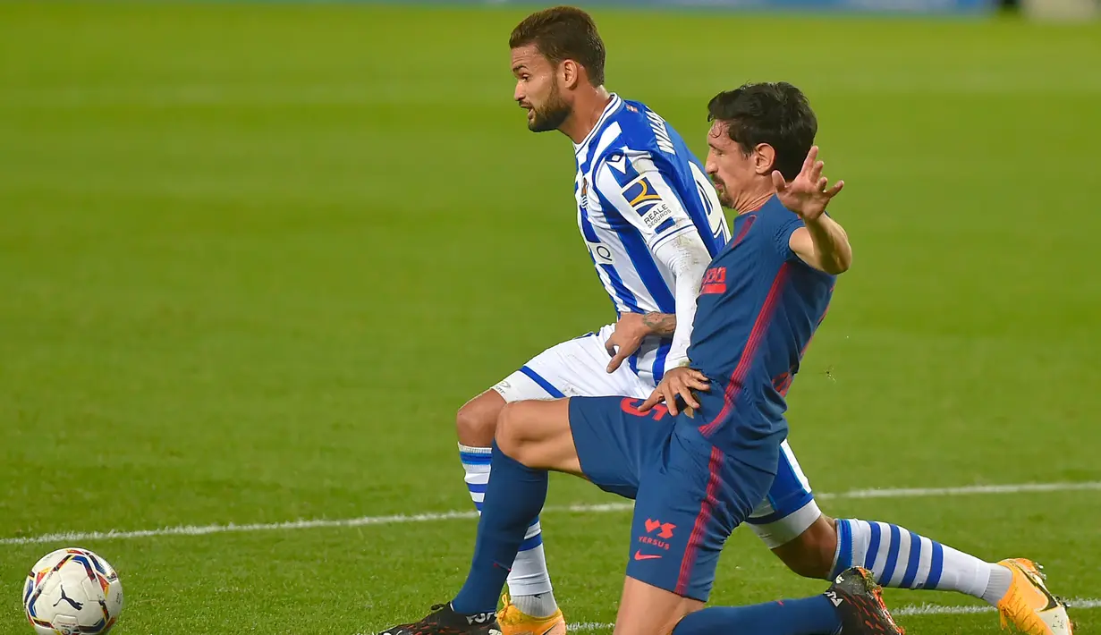 Gelandang Atletico Madrid, Lucas Torreira, berebut bola dengan penyerang Real Sociedad, Willian Jose, pada laga lanjutan Liga Spanyol di Anoeta Stadium, Rabu (23/12/2020) dini hari WIB. Atletico Madrid menang 2-0 atas Real Sociedad. (AFP/Ander Gillenea)