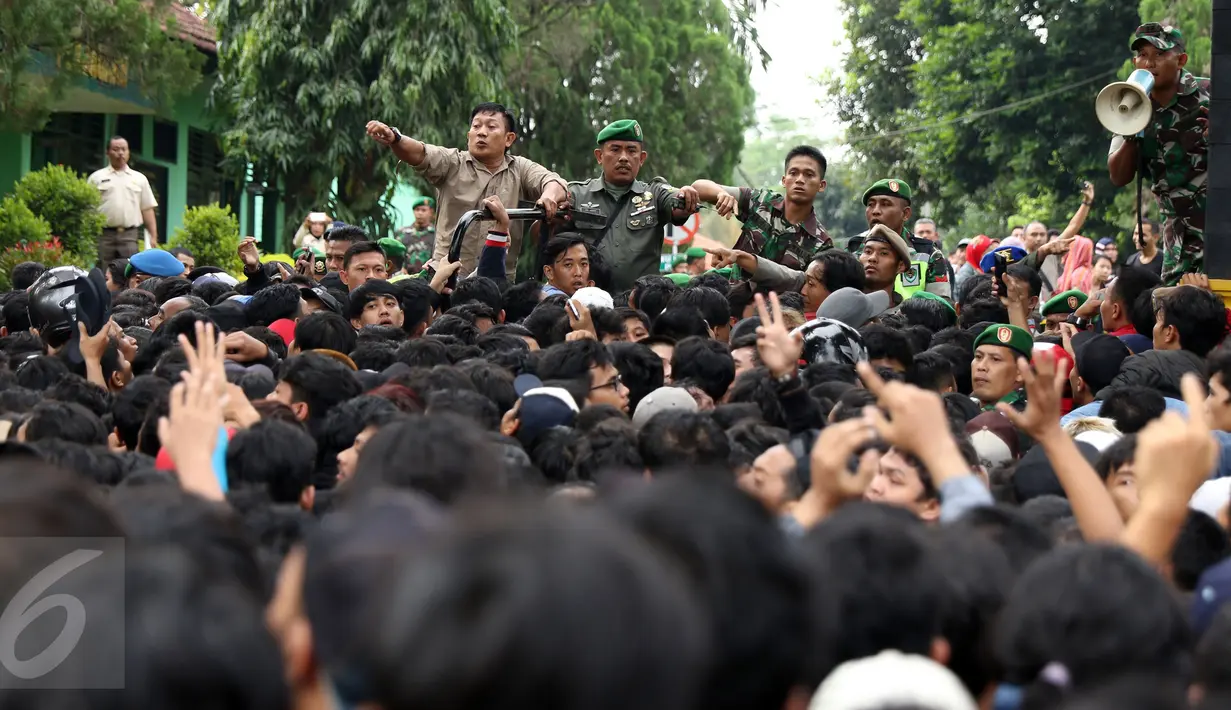 Petugas gabungan mengatur suporter yang antri masuk ke halaman Kodim 0621 Surya Kancana Kab Bogor, Selasa (13/12). 5000 lembar tiket final Piala AFF 2016 antara Indonesia vs Thailand dijual di Kodim 0621 Surya Kancana. (Liputan6.com/Helmi Fithriansyah)