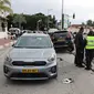 Personel darurat dan keamanan Israel berdiri di samping mobil yang rusak usai serangan teroris di pusat Kota Raanana, pada 15 Januari 2024. (Jack Guez / AFP)