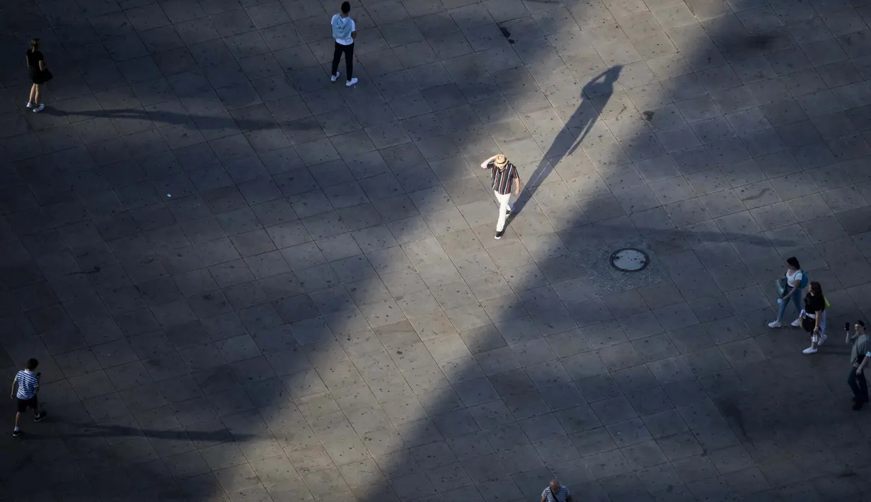 Seorang pria berjalan di bawah sinar matahari sore sambal melintasi pejalan kaki Alexanderplatz di Berlin, Jerman, 17 Agustus 2020. (Christoph Soeder / dpa via AP)