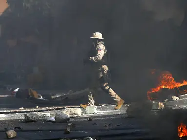 Polisi membersihkan jalan dari batu dan ban yang dibakar oleh pengunjuk rasa yang marah dengan meningkatnya kekerasan di lingkungan Lalue, Port-au-Prince, Haiti, Rabu (14/7/2021). Presiden Haiti Jovenel Moise dibunuh pada 7 Juli. (AP Photo/Fernando Llano)