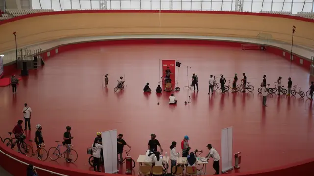 Lanskap area Jakarta International Velodrome dari kursi penonton. Nampak barisan peserta mengantre untuk registrasi dan bergantian menunggu giliran berfoto dengan background merah bertuliskan Lensa Community dan Ride to 500.