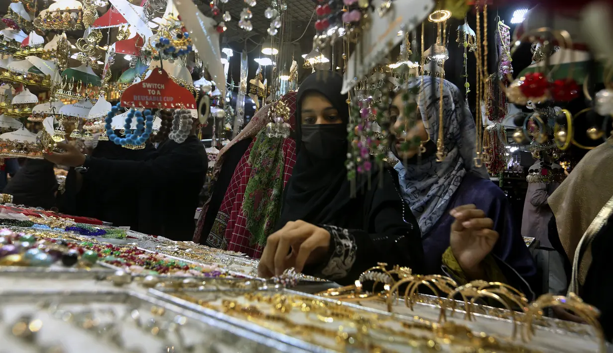 <p>Gadis-gadis muda melihat-lihat perhiasan buatan tradisional saat dia dan yang lainnya mengunjungi pasar untuk berbelanja perayaan Idul Fitri mendatang, di Karachi, Pakistan, Jumat, 29 April 2022. Idul Fitri menandai akhir bulan suci Ramadhan. (AP Photo/Fareed Khan)</p>