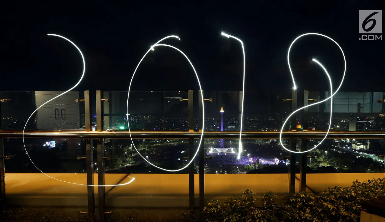 Coretan lampu tahun 2018 menghiasi malam pergantian tahun baru di kawasan silang Moumen Nasional (Monas), Jakarta, Senin (1/1/2018). (Liputan6.com/Johan Tallo)