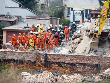 Petugas penyelamat mencari korban di reruntuhan sebuah apartemen tua yang ambruk di Swiebodzce, Polandia, Sabtu (8/4). Akibat insiden itu, 5 orang dikabarkan tewas, sementara 4 orang lainnya luka-luka, dan 1 orang hilang. (Natalia DOBRYSZYCKA/AFP)