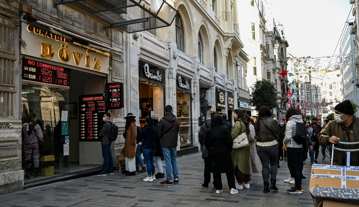 Orang-orang menunggu di luar agen penukaran mata uang dekat alun-alun Taksim ketika lira Turki terperosok ke level terendah sepanjang sejarah di Istanbul, Senin (25/10/2021). Lira melemah imbas pengusiran duta besar AS dan sembilan negara Barat lainnya oleh Presiden Tayyip Erdogan. (Ozan KOSE/AFP)