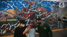 Warga berswafoto dengan latar belakang mural kolaborasi di Terowongan Kendal, Kawasan TOD Dukuh Atas, Jakarta, Rabu (6/7/2022). Disney Indonesia berkolaborasi bersama Jakarta Experience Board (JXB) dan Kita Art Friends menghadirkan karya seni mural terinspirasi dari film Marvel Studios "Thor: Love and Thunder." (Liputan6.com/Faizal Fanani)