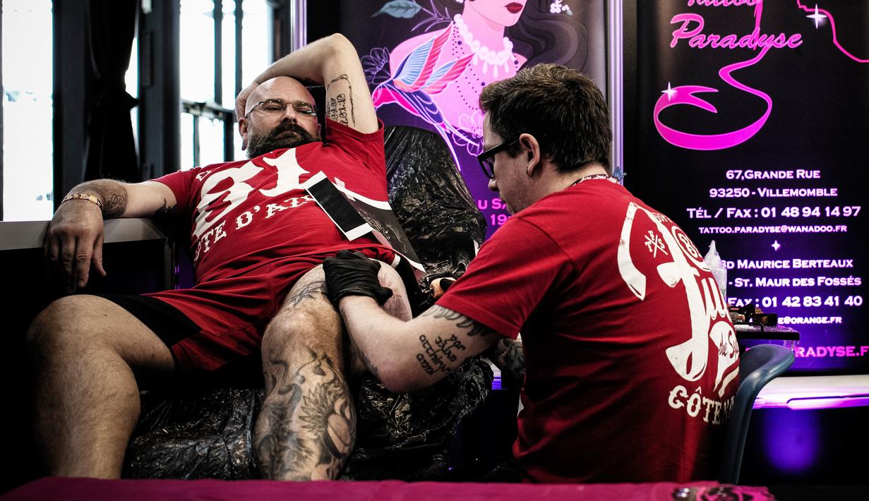 Seorang pria membuat tato di pahanya saat Paris Tattoo Convention di Grand Halle de la Villette, Paris, Prancis, Jumat (9/3). Paris Tattoo Convention tahun ini merupakan yang kedelapan. (Philippe LOPEZ/AFP)