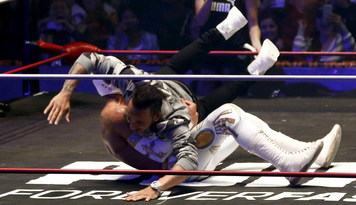 Pebalap F1 dari tim Mercedes GP, Lewis Hamilton berusaha menjatuhkan pegulat yang bintang WWE di Coliseo Arena, Mexico City, (28/10/2015). (Reuters/Henry Romero)
