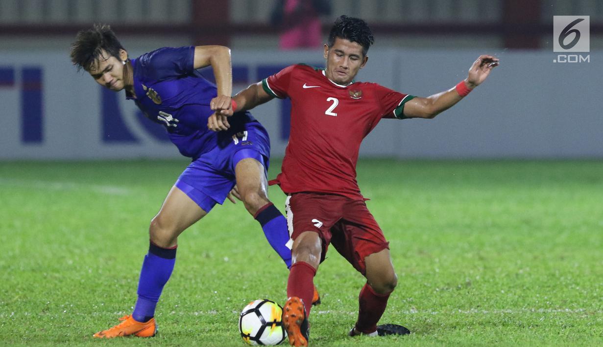 Bek Timnas Indonesia U-23, I Putu Gede Juni Antara (kanan) berebut bola dengan pemain Thailand U-23, Poramet Arjvilai pada laga persahabatan di Stadion PTIK, Jakarta, Kamis (31/5). Indonesia U-23 kalah 1-2. (Liputan6.com/Helmi Fithriansyah)
