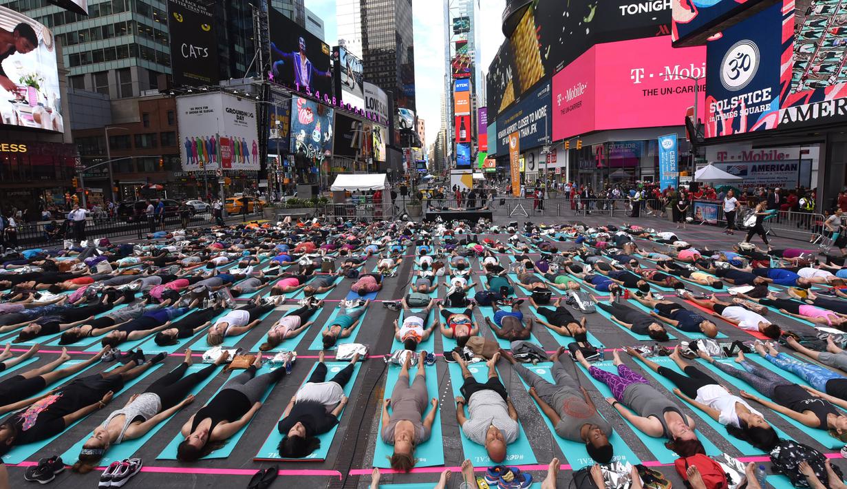 Warga ambil bagian berlatih yoga bersama di kawasan Times Square, New York pada 'Summer Solstice' atau hari dengan siang terpanjang di musim panas, Rabu (21/6). Acara itu menandai Hari Yoga Internasional yang jatuh pada 21 Juni. (TIMOTHY A. CLARY/AFP)