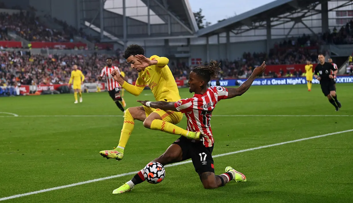 Gelandang Liverpool, Curtis Jones (kiri) melompati tantangan dari striker Brentford Ivan Toney pada matchday keenam Liga Inggris di Brentford Community Stadium, Sabtu (25/9/2021). Liverpool ditahan imbang 3-3 oleh tuan rumah Brentford. (Glyn KIRK / AFP)