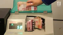 Petugas tengah menghitung uang rupiah menggunakan mesin di Bank BUMN, Jakarta, Selasa (17/4). Rupiah siang ini melemah dibandingkan tadi pukul 09.00 WIB di level Rp 13.771 per dolar AS. (Liputan6.com/Angga Yuniar)