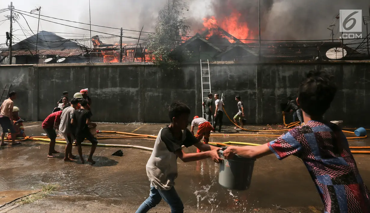 Warga mencoba memadamkan api yang membakar pemukiman padat penduduk di kawasan Manggarai, Jakarta, Rabu (10/7/2019). Tidak ada laporan korban dalam kebakaran ini, sementara kerugian yang diderita masih dalam penanganan petugas di lokasi. (Kapanlagi.com/Budy Santoso)
