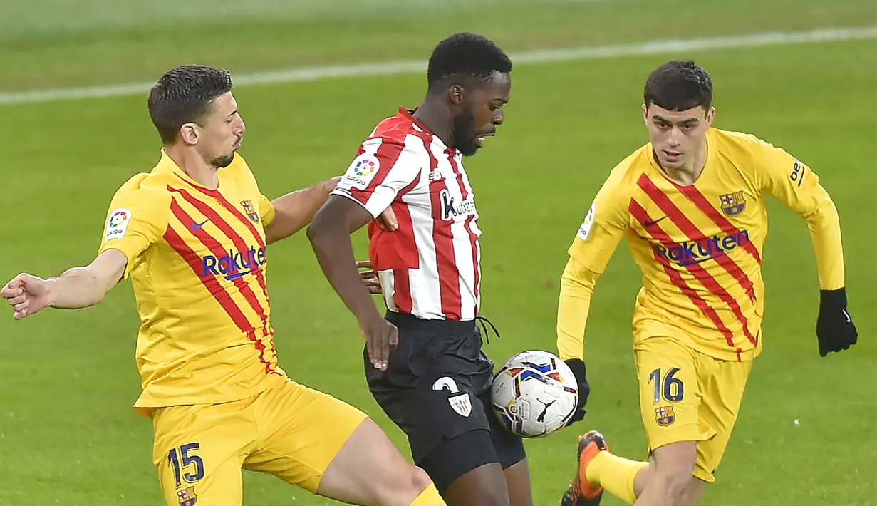 Striker Athletic Bilbao, Inaki Williams (tengah) dikepung dua pemain Barcelona, Clement Lenglet (kiri) dan Pedri dalam laga lanjutan Liga Spanyol 2020/21 di San Mames Stadium, Bilbao, Rabu (6/1/2021). Athletic Bilbao kalah 2-3 dari Barcelona. (AFP/Ander Gillenea)